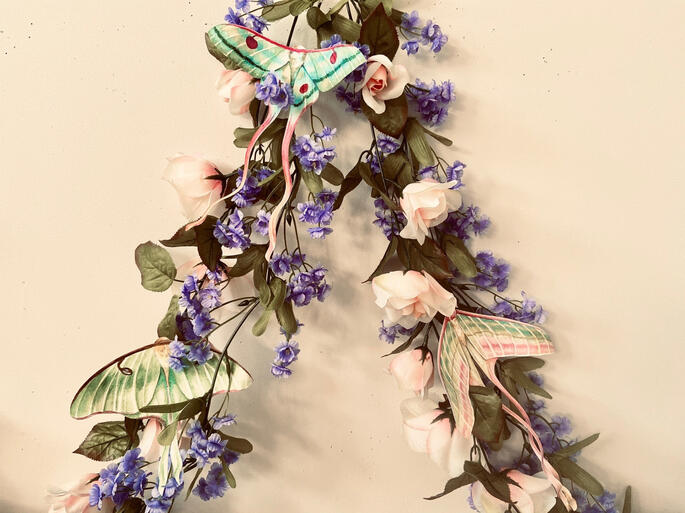 more moths of similar color intertwined with vines of purple and pink flowers.